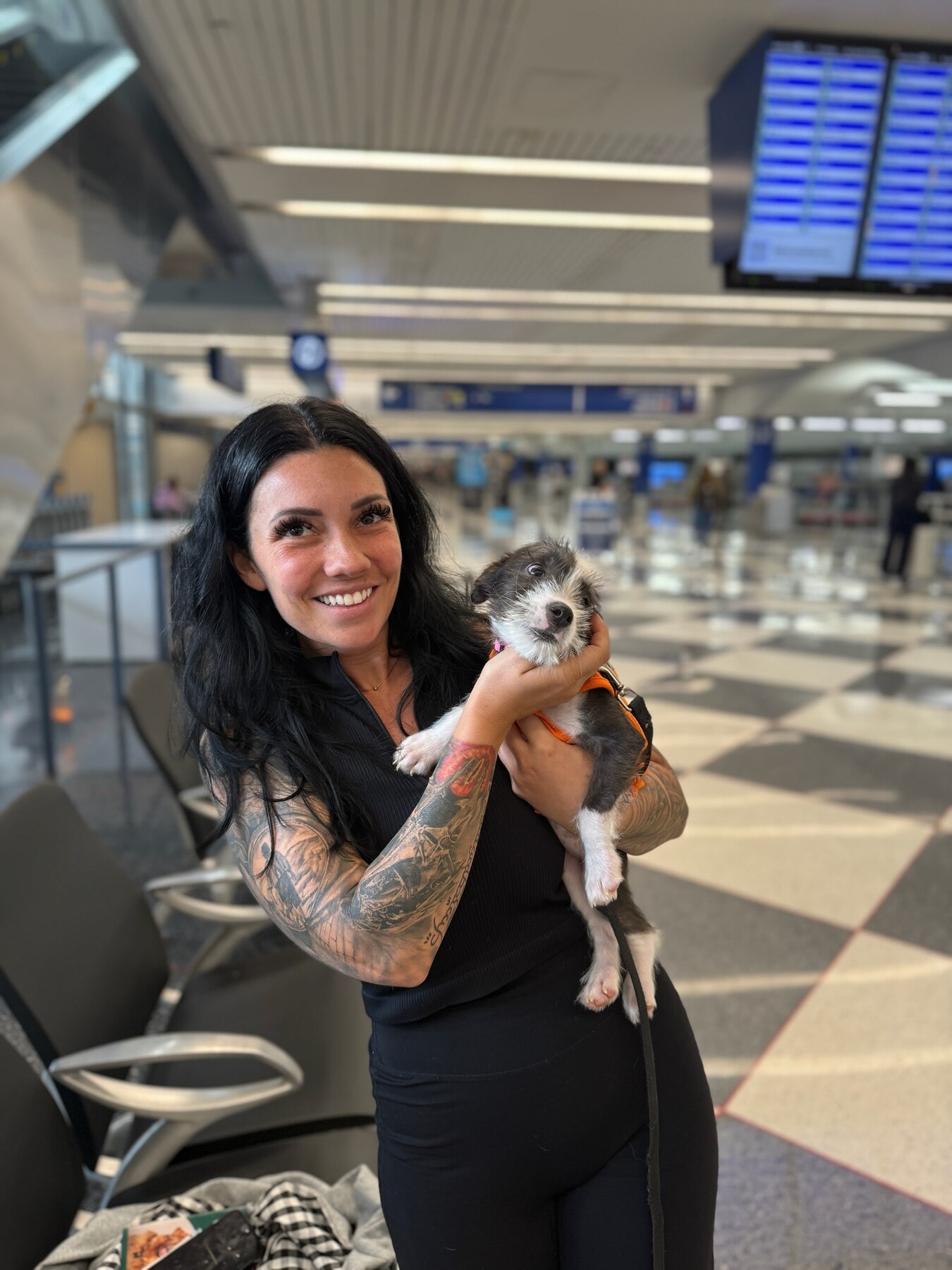 A real Pet Commute flight nanny holding a small dog inside an airport